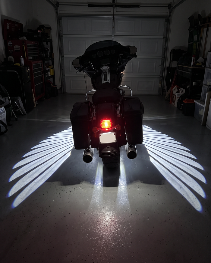 Bagger with glowing angel wings in a dark garage